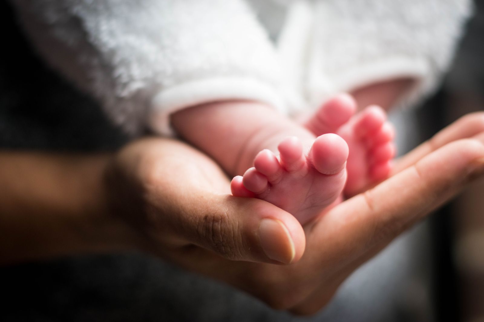 A parent tenderly holding their baby's feet in their cupped hands