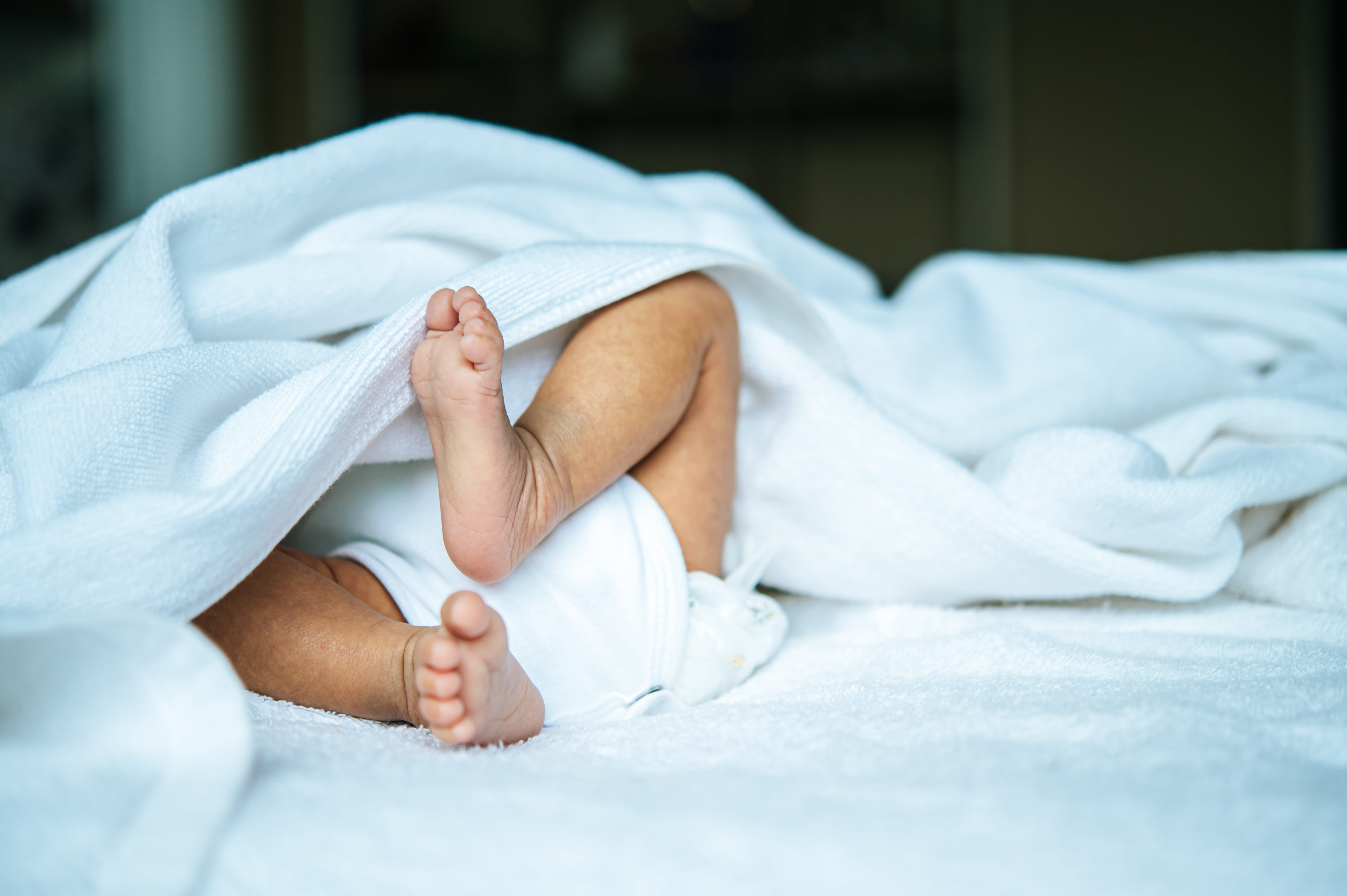 A baby's feet resting on a soft white blanket