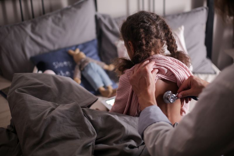 A doctor examining a child's back with a stethoscope