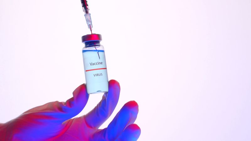 A vaccine vial and syringe held in a gloved hand